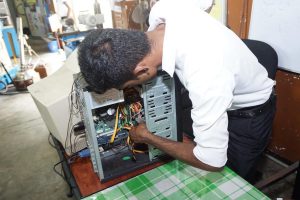 a man in a white shirt is working on a computer - Hardware technician